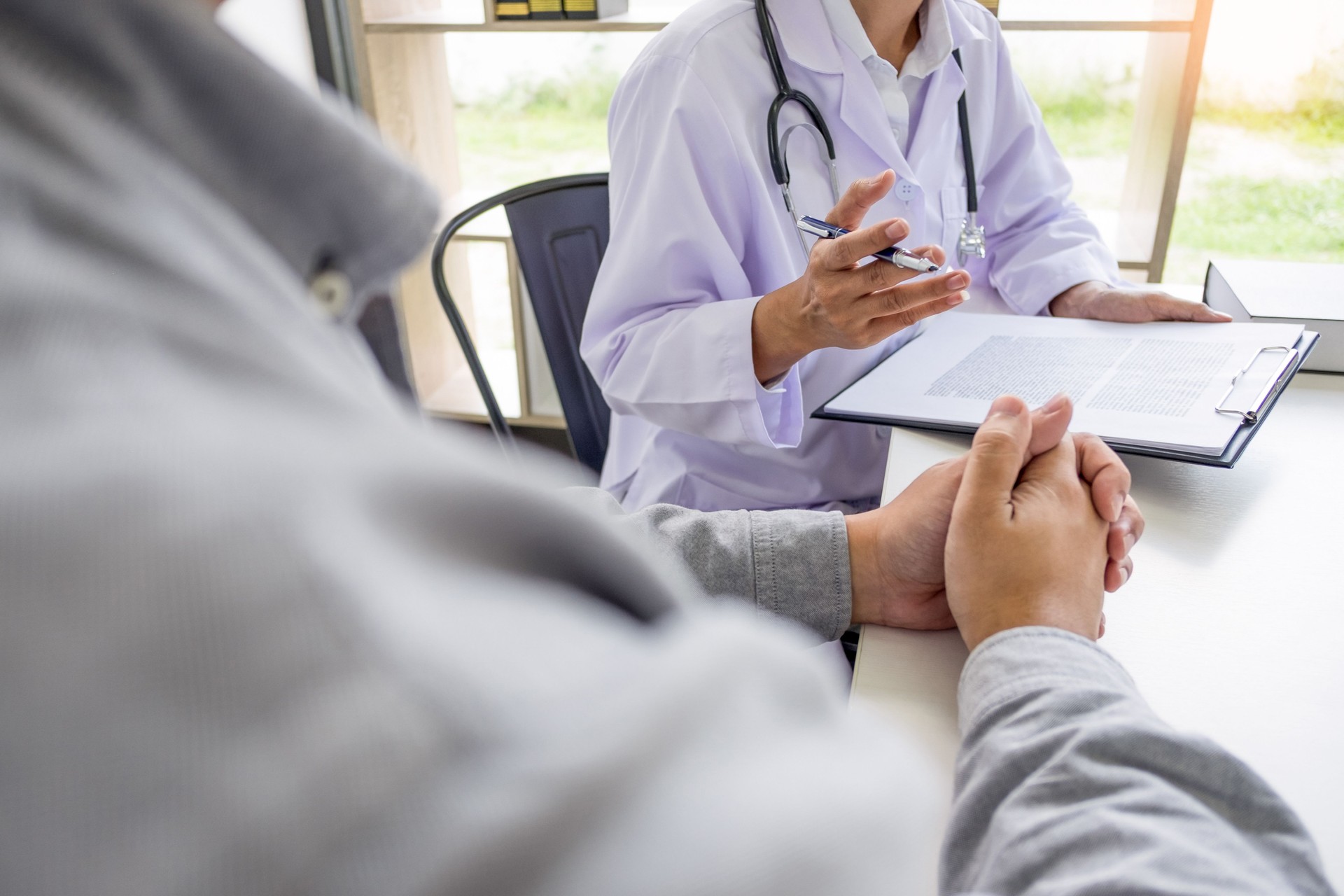 Sección media del médico y el paciente hablando en el consultorio